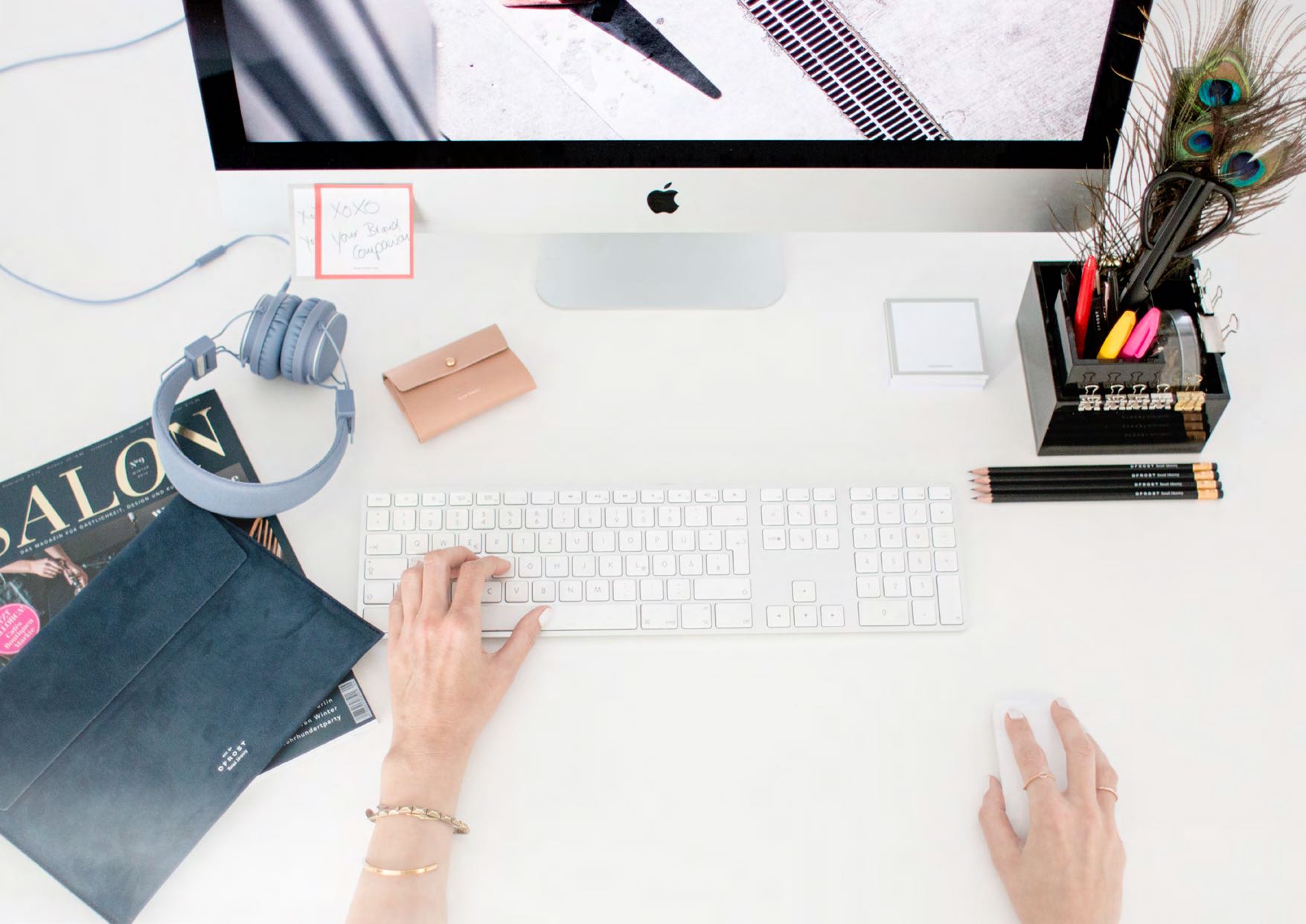 Arbeitsplatz mit minimalistischer Ästhetik, ausgestattet mit hochwertigen Accessoires und einem iMac, präsentiert im Rahmen der Kooperation zwischen DFROST und AYASSE, kuratiert von MORE PIOUS STUDIOS.