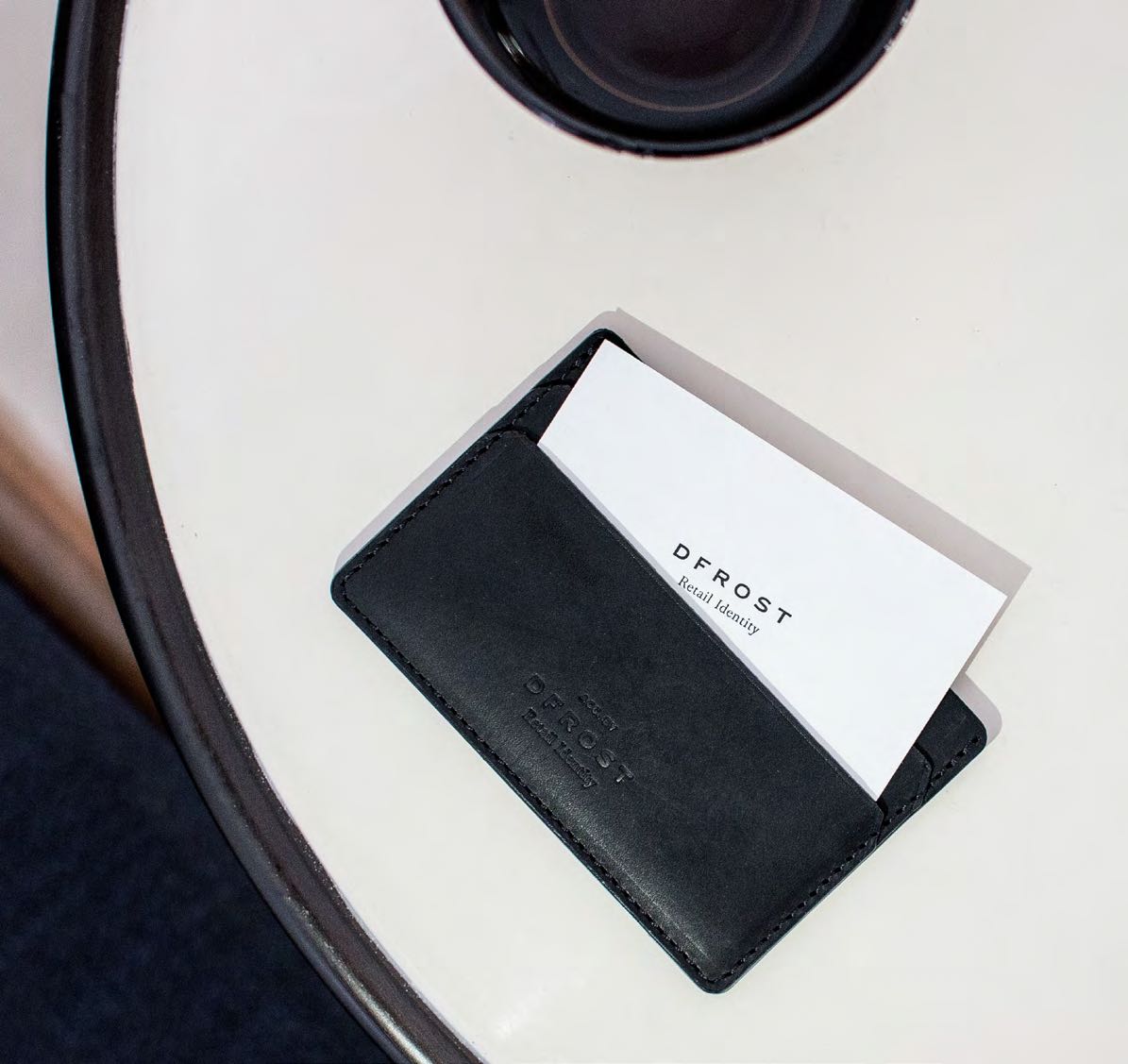 Visitenkartenhalter aus schwarzem Leder von AYASSE, elegant platziert auf einem Tisch, präsentiert durch MORE PIOUS STUDIOS im Rahmen des DFROST x AYASSE Projekts.