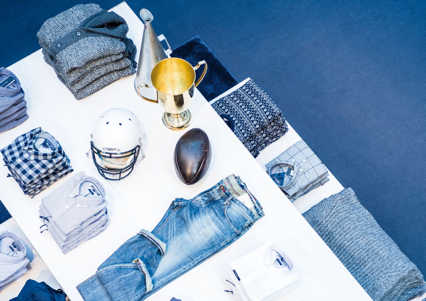 Vogelperspektive auf Modepräsentation mit Jeans, Pullovern und Lifestyle-Elementen, entworfen von MORE PIOUS STUDIOS.