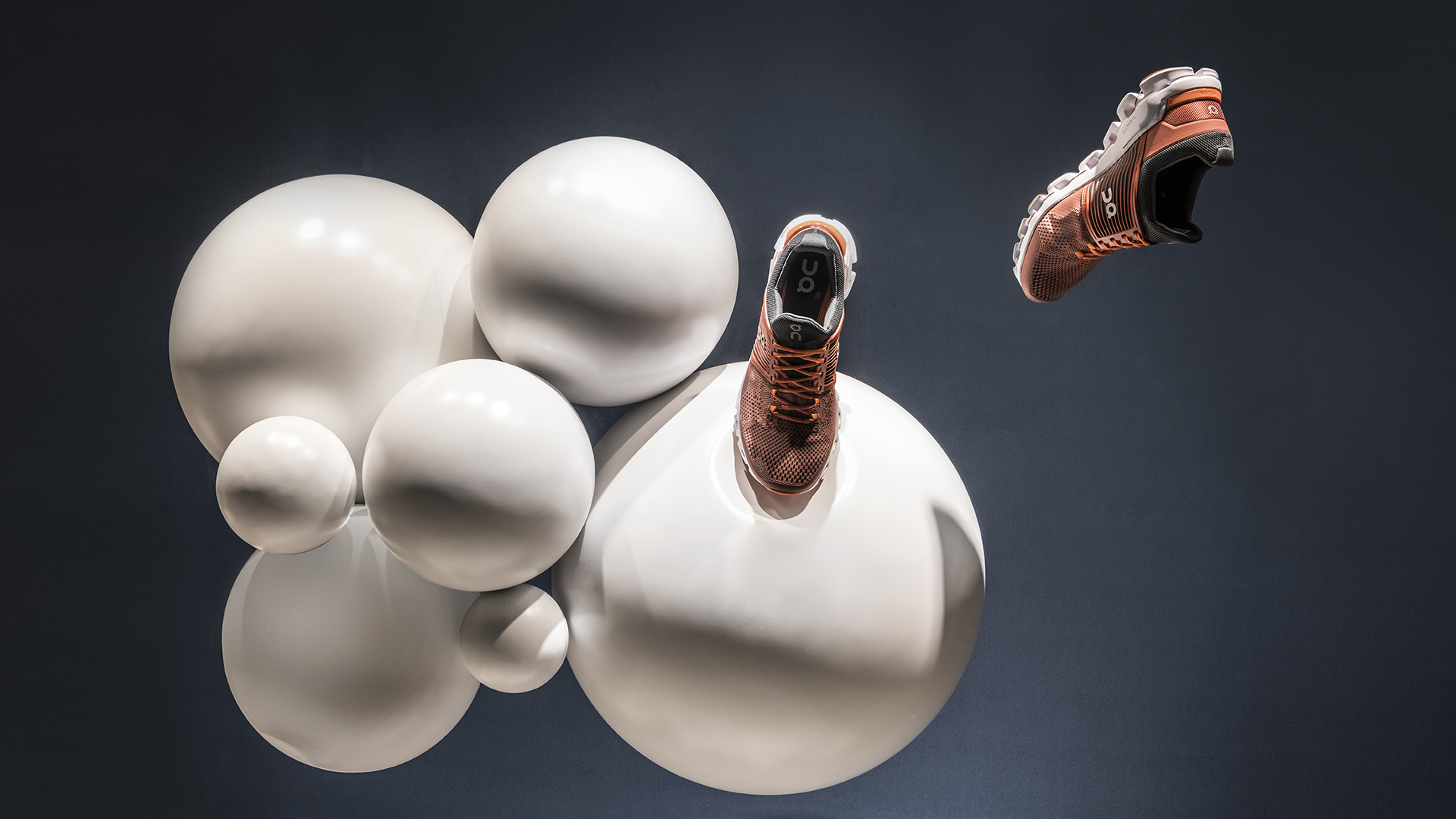 Schwebeeffekt-Darstellung eines ON Helion Schuhs mit weißen Kugeln als Designhintergrund