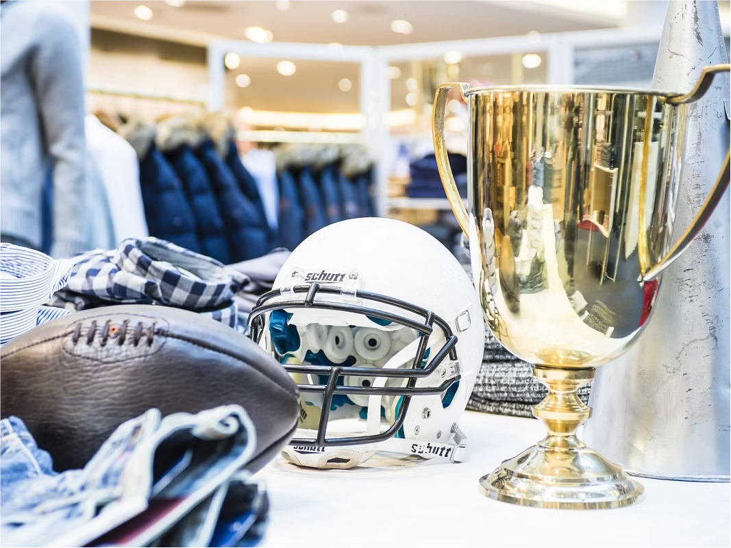 Detailansicht mit sportlichen Accessoires wie einem Footballhelm und Pokal im Pop-up-Store Homecoming, gestaltet von MORE PIOUS STUDIOS.