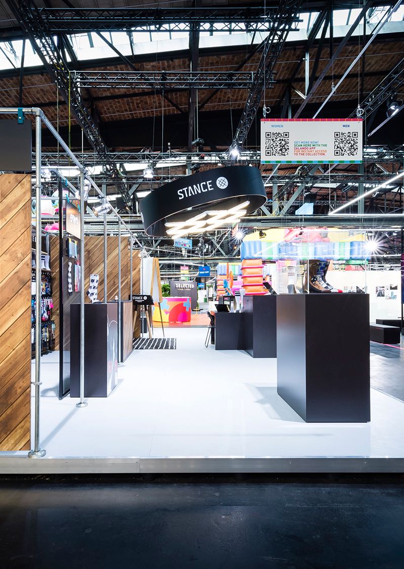 Rückansicht des STANCE Messestands auf der Bread & Butter Messe mit innovativer Hängebeleuchtung und offenen Strukturen, gestaltet von MORE PIOUS STUDIOS.