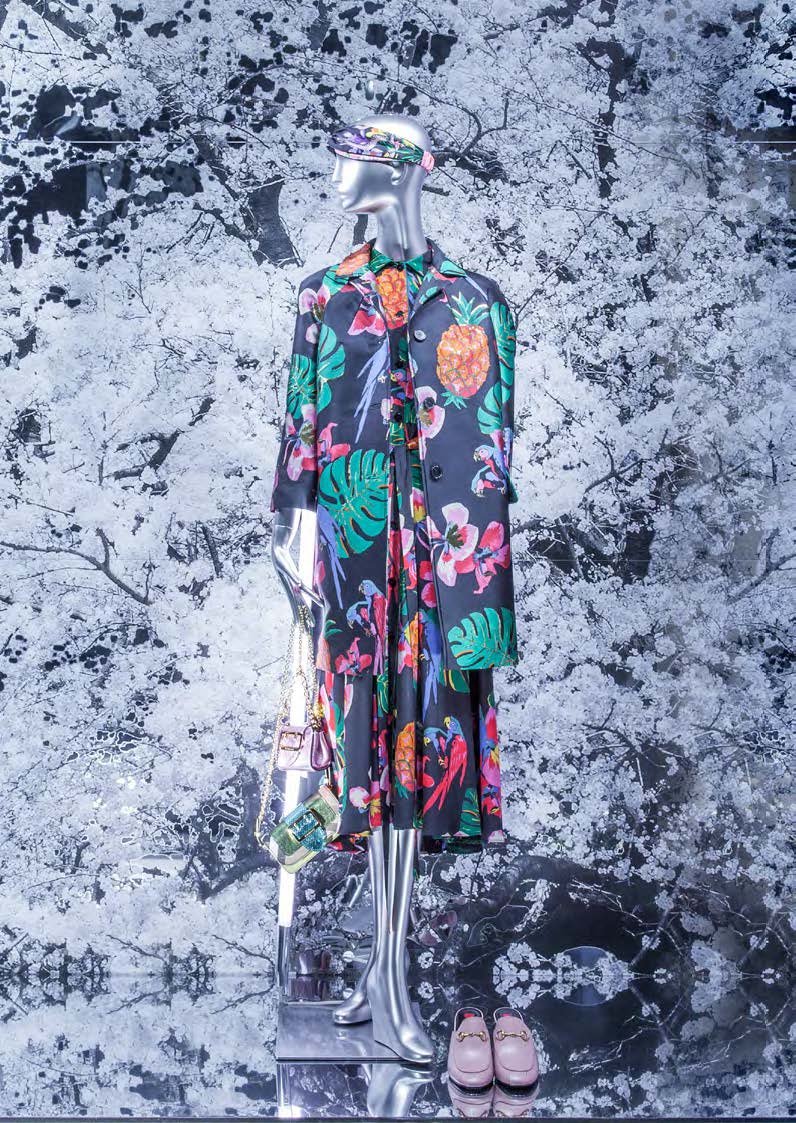 Nahaufnahme eines Mannequins mit tropischem Outfit und floralen Mustern vor einer Kulisse aus Kirschblüten, gestaltet von MORE PIOUS STUDIOS.