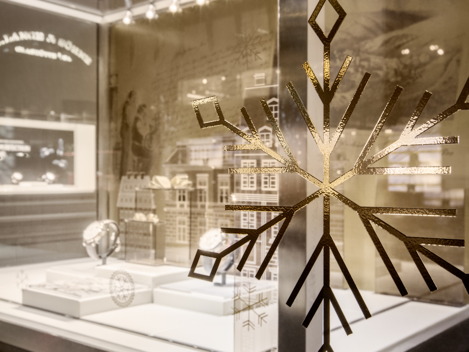 Nahaufnahme eines dekorativen Schneeflockenmotivs auf einem Schaufenster von A. Lange & Söhne.