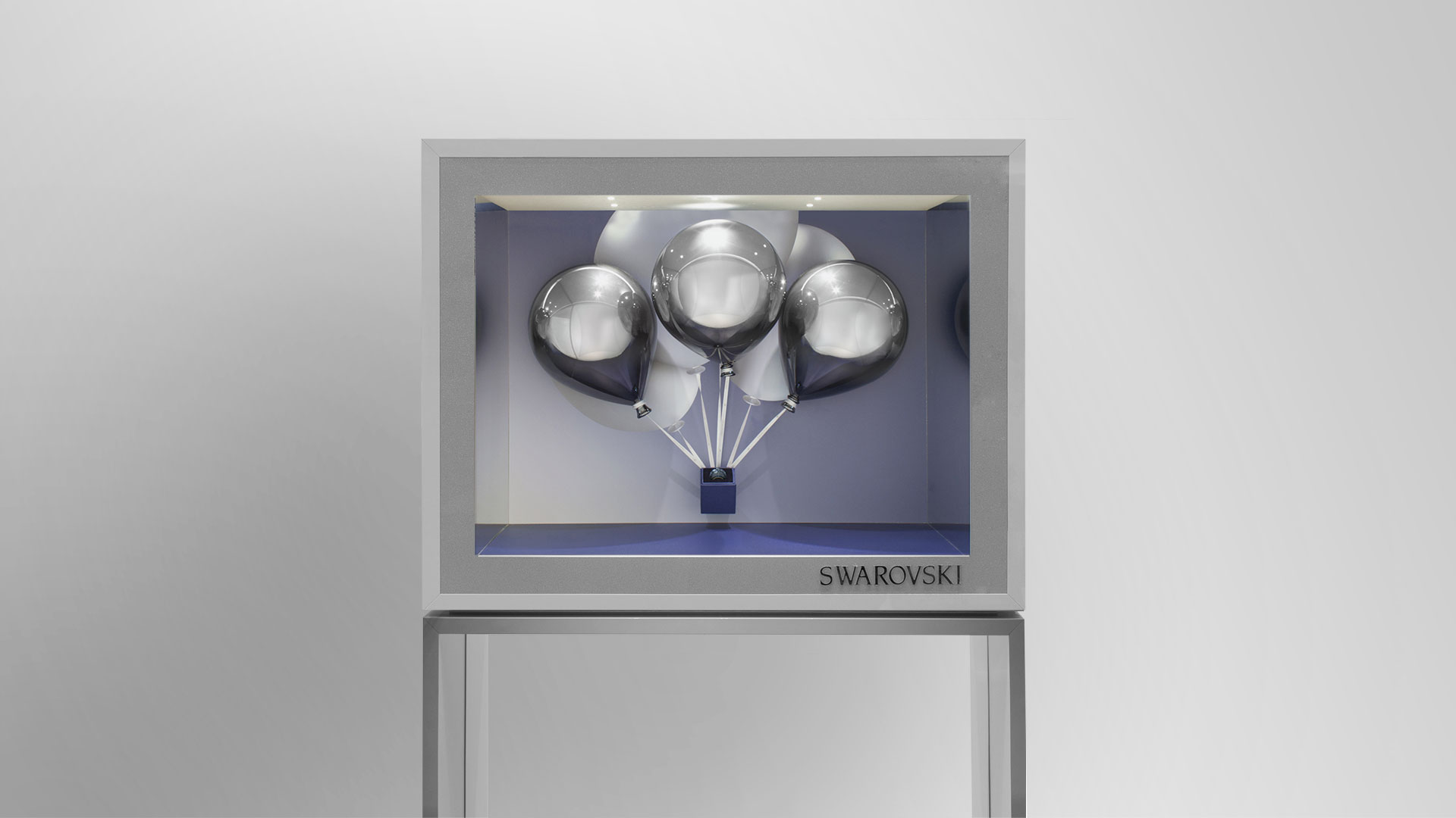 Freistehendes Swarovski-Schaufenster mit silbernen Luftballons und minimalistischer Präsentation.