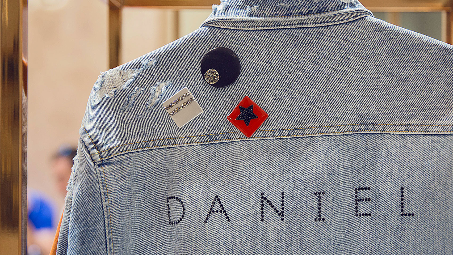 Rückenansicht einer Jeansjacke mit personalisierten Swarovski-Ansteckern und dem Namen „DANIEL“.