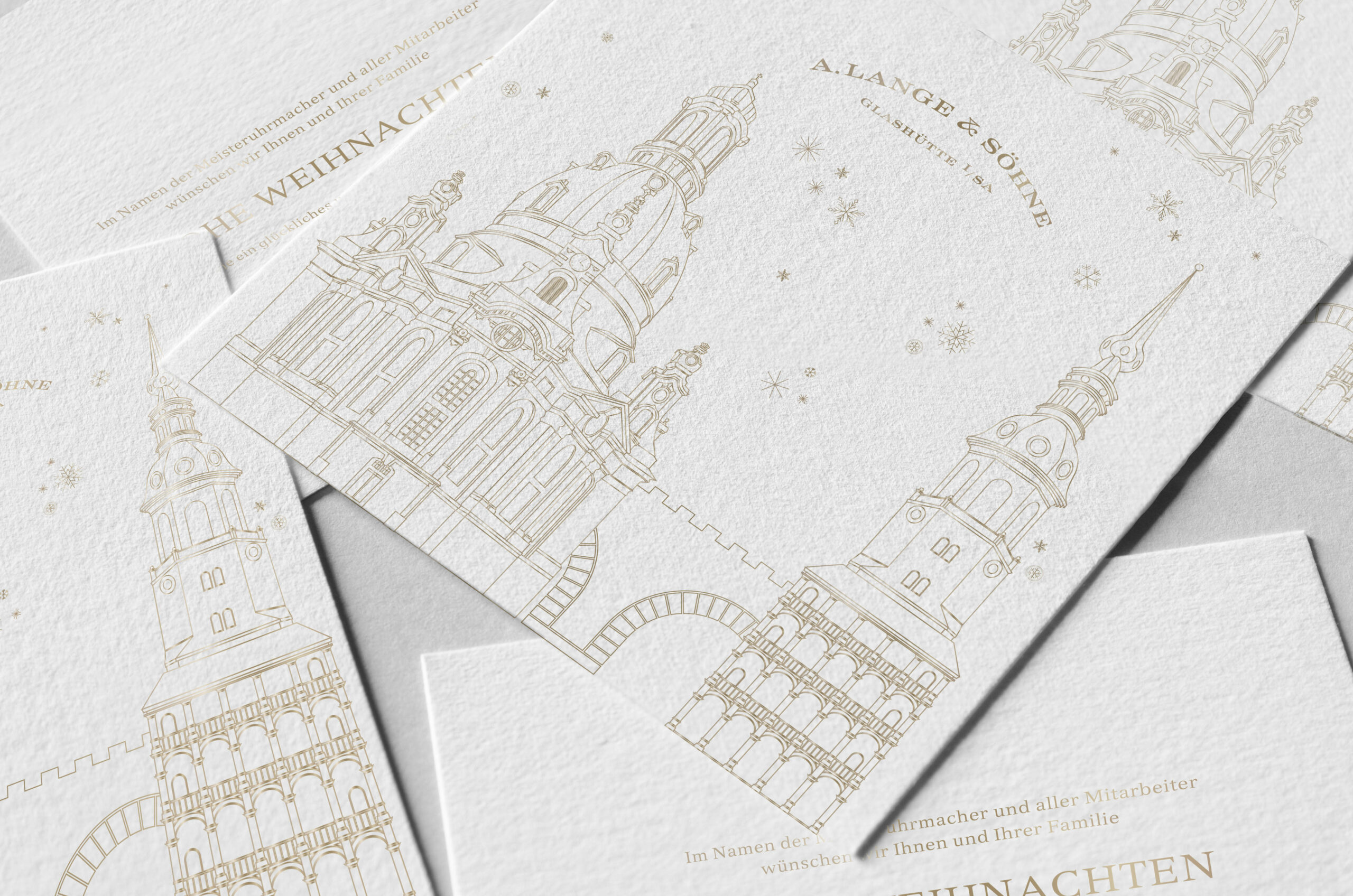 Detailaufnahme von Weihnachtskarten von A. Lange & Söhne mit goldener Architektur und filigranem Design.